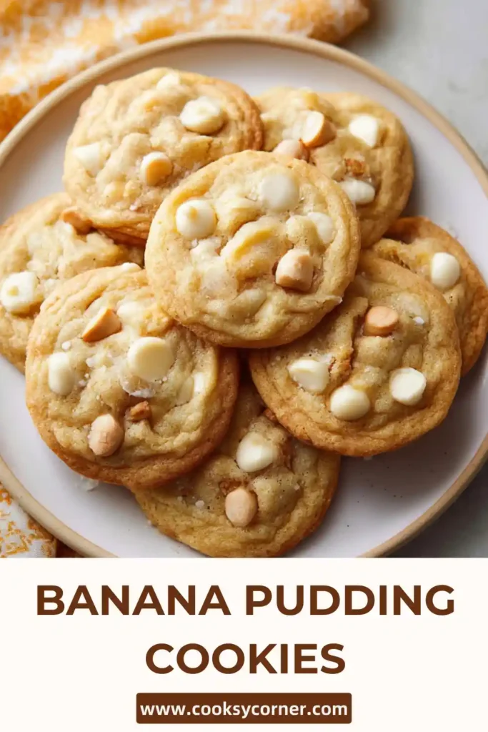 Freshly baked Banana Pudding Cookies cooling on a rack with melted white chocolate chips. The cookies appear thick and soft.