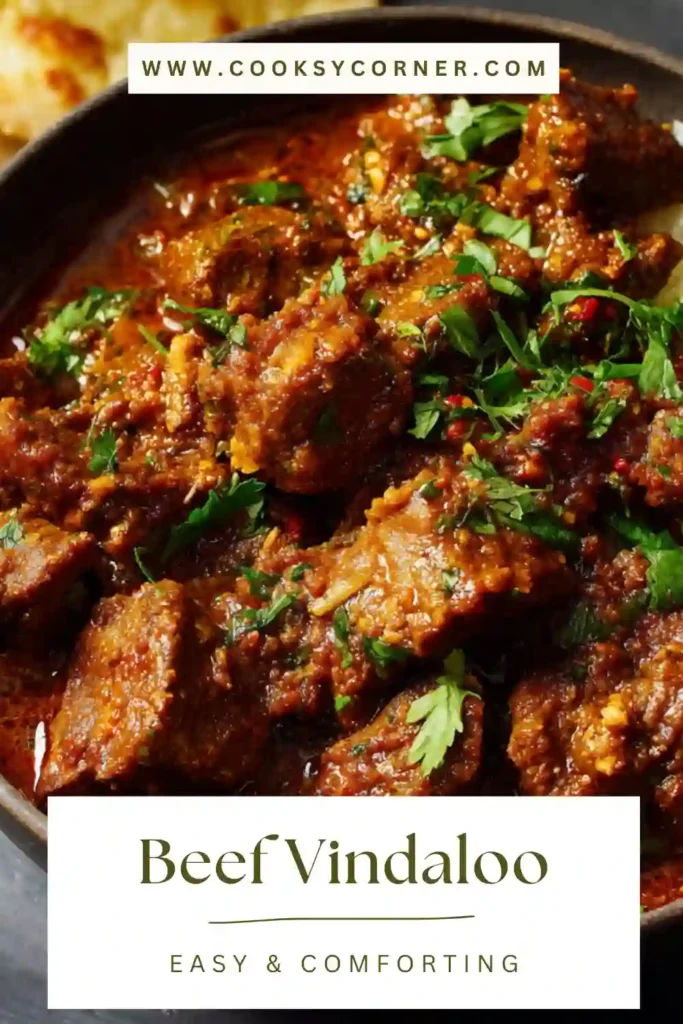 A bowl of Beef Vindaloo featuring tender chunks of beef in a rich red spicy curry sauce garnished with fresh cilantro. The authentic Indian beef vindaloo is served hot and aromatic.