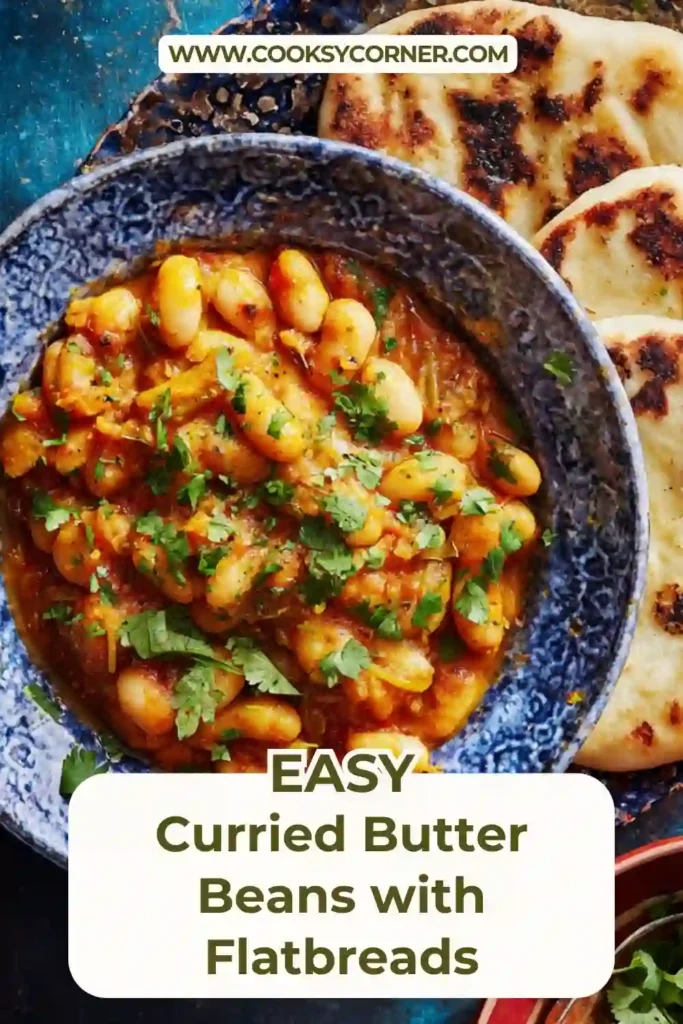 Bowl of curried butter beans with cherry tomatoes and fresh coriander served with warm flatbreads.