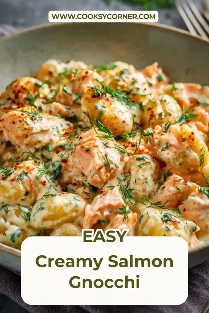 Close-up of creamy gnocchi with smoked salmon and spinach in a rich sauce, topped with freshly chopped herbs.