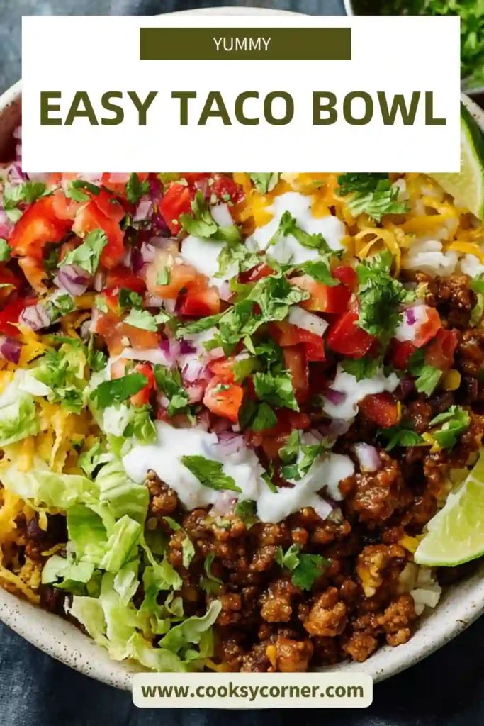 A colorful easy taco bowl with ground beef, rice, black beans, corn, avocado, and cheese arranged beautifully in a bowl.