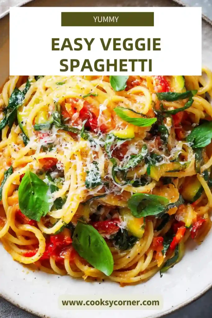 Vegetarian spaghetti pasta served with colorful vegetables and tomato sauce. The dish is garnished with basil leaves and grated parmesan.
