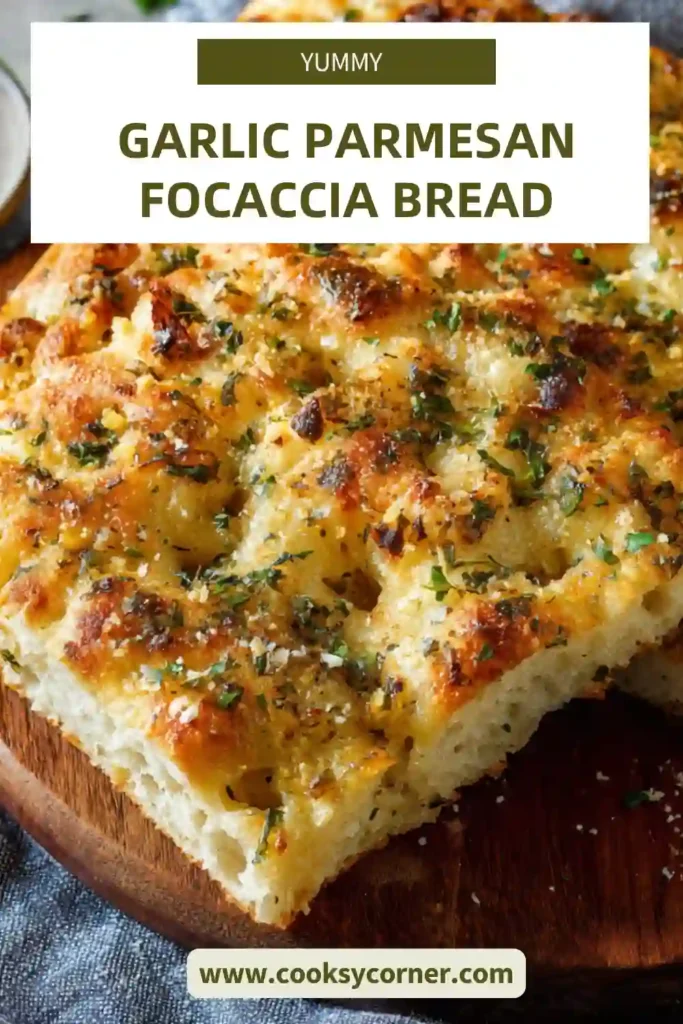 Garlic parmesan focaccia bread with golden crust and visible herbs baked in a round pan. The surface is dimpled and topped with cheese and garlic.