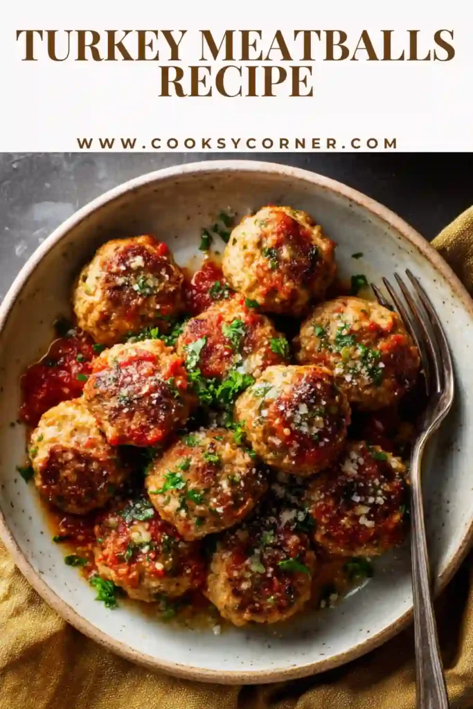 Close-up of homemade turkey meatballs served with pasta and marinara sauce. The dish is garnished with Parmesan cheese and herbs.