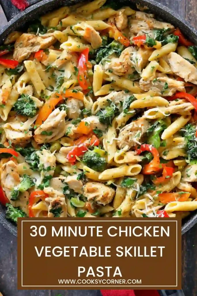 Overhead view of a pan of 30 Minute Chicken Vegetable Skillet Pasta with herbs sprinkled on top. Bright vegetables add visual appeal.