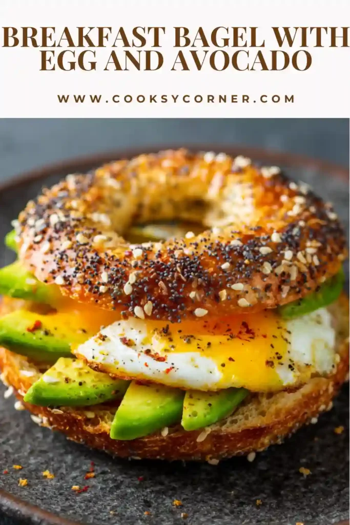 A breakfast bagel filled with avocado, fried egg, melted cheese, and pickled onions on a wooden board. The textures look creamy and fresh.
