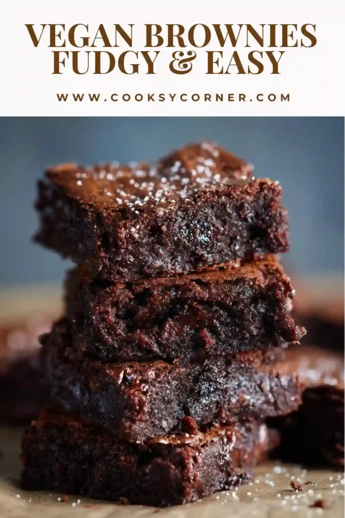 Homemade vegan brownies in a baking pan lined with parchment paper, freshly baked and slightly cracked on top.