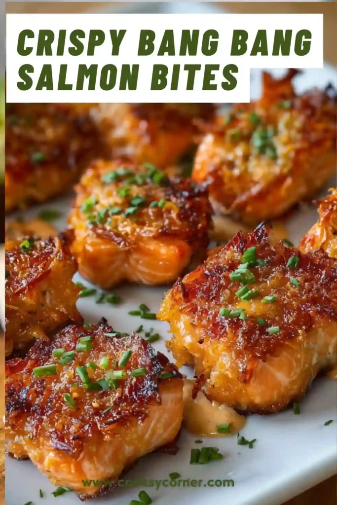 A bowl of Crispy Bang Bang Salmon Bites coated in creamy spicy sauce and topped with sesame seeds and green onions. The salmon pieces are golden brown and perfectly crispy.