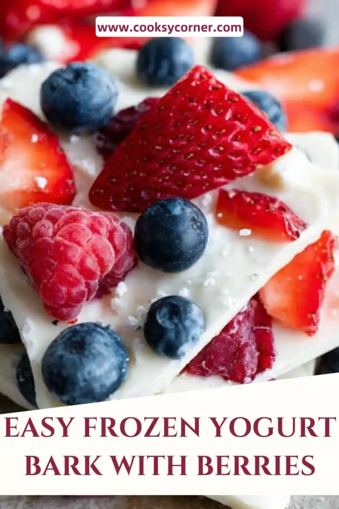 Frozen yogurt bark with berries spread on a baking sheet, topped with strawberries, blueberries, and coconut flakes. The texture looks creamy and refreshing.