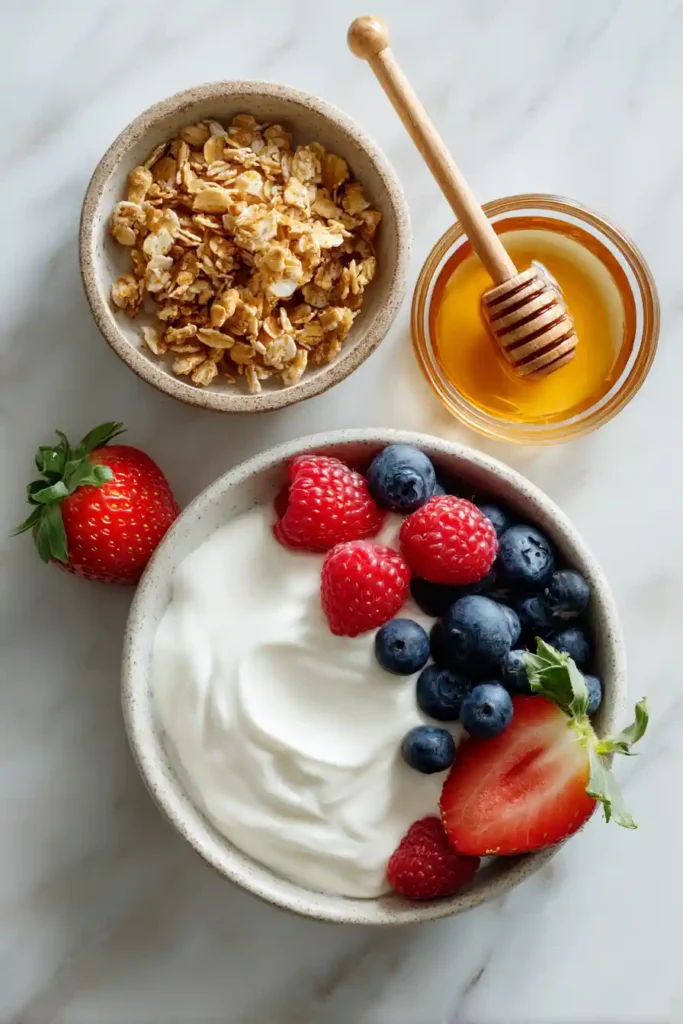 A homemade Greek Yogurt Parfait topped with granola, fresh berries, and a drizzle of honey. Served in a clear glass to highlight the colorful layers.