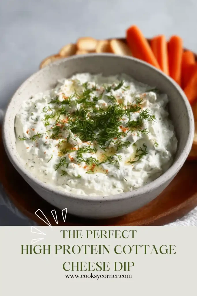Close-up of a creamy blended cottage cheese dip in a white bowl with fresh herbs. The high protein dip is served alongside crunchy vegetables and crackers.