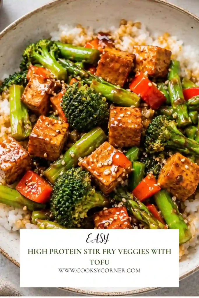 High Protein Stir Fry Veggies with Tofu served in a bowl with colorful vegetables, ramen noodles, smoked tofu, and fresh basil. The stir fry is coated in a glossy sesame sauce for a vibrant vegan meal.