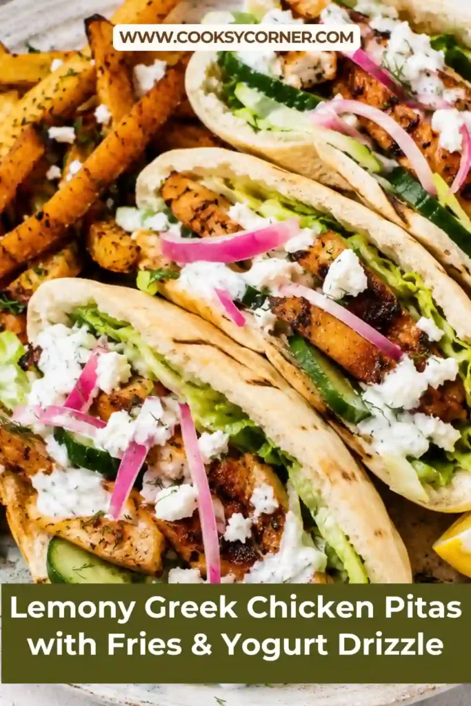 Close-up of homemade Lemony Greek Chicken Pitas topped with feta, dill, cucumber, and herbed yogurt drizzle. Crispy roasted fries add a delicious finishing touch.