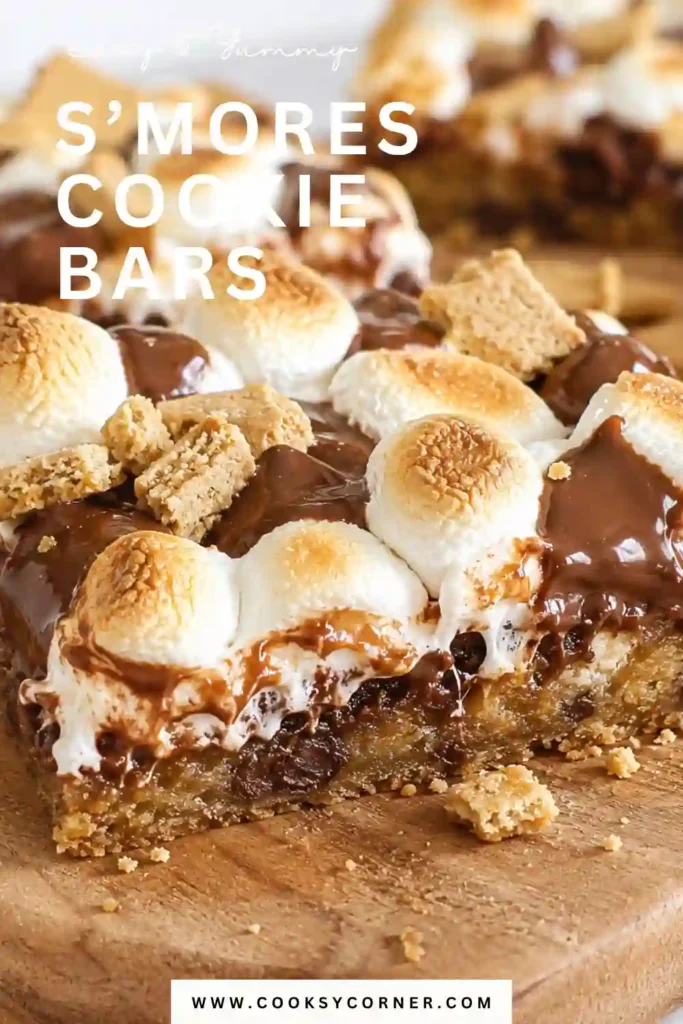 Freshly baked S’mores Cookie Bars topped with melted chocolate and gooey marshmallow layers on a dessert tray.