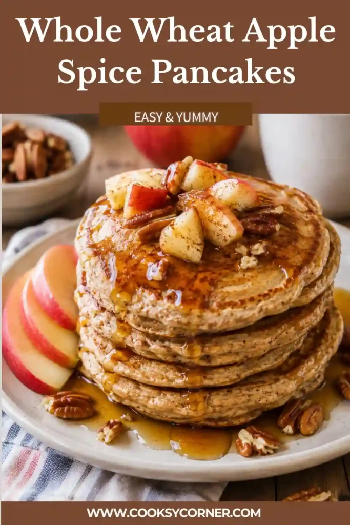 A stack of Whole Wheat Apple Spice Pancakes topped with maple syrup and fresh apple slices. The fluffy pancakes feature warm cinnamon flavors and crunchy pecans for a wholesome breakfast.