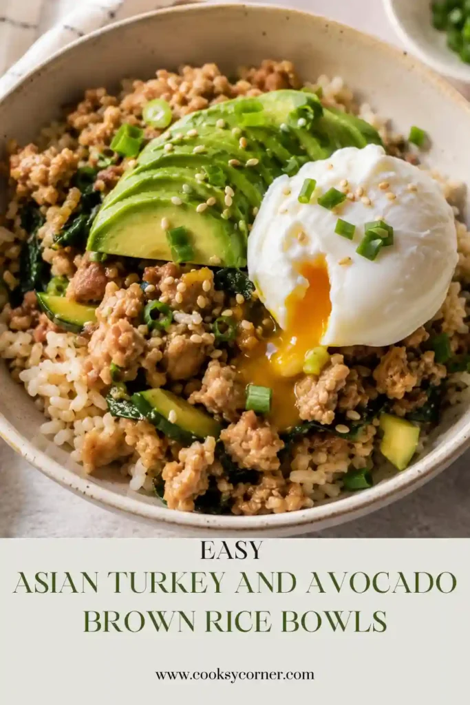Fresh Asian-inspired brown rice bowl loaded with ground turkey, avocado slices, zucchini, sesame seeds, green onions, and a soft poached egg for a balanced high-protein meal.