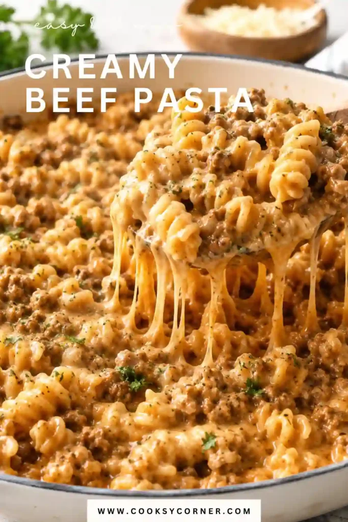 Close-up of cheesy creamy beef pasta served warm with parsley garnish. The rich sauce coats every piece of rotini for a comforting homemade meal.