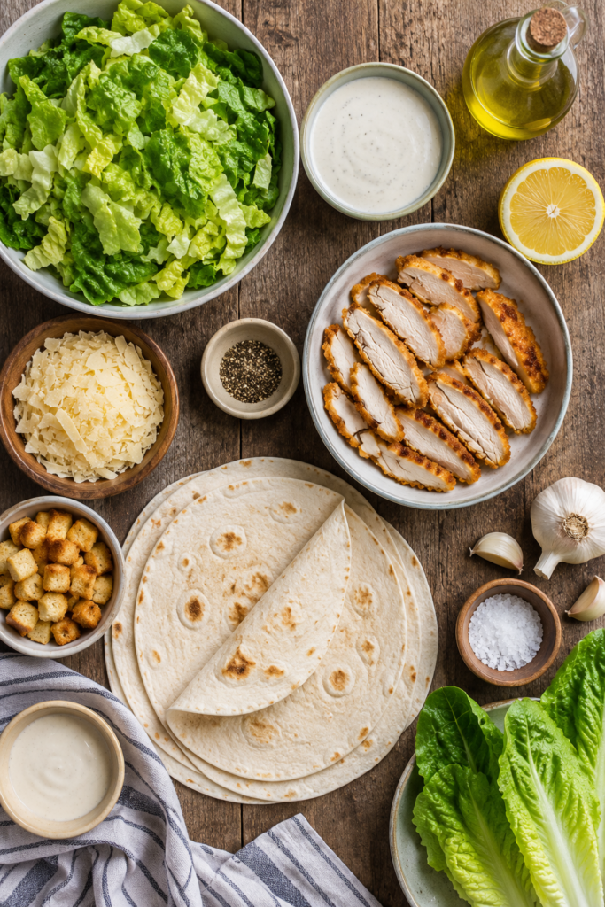 Crispy chicken Caesar wraps arranged on a serving platter with fresh romaine lettuce and Caesar dressing. An easy wrap recipe perfect for meal prep and family meals.