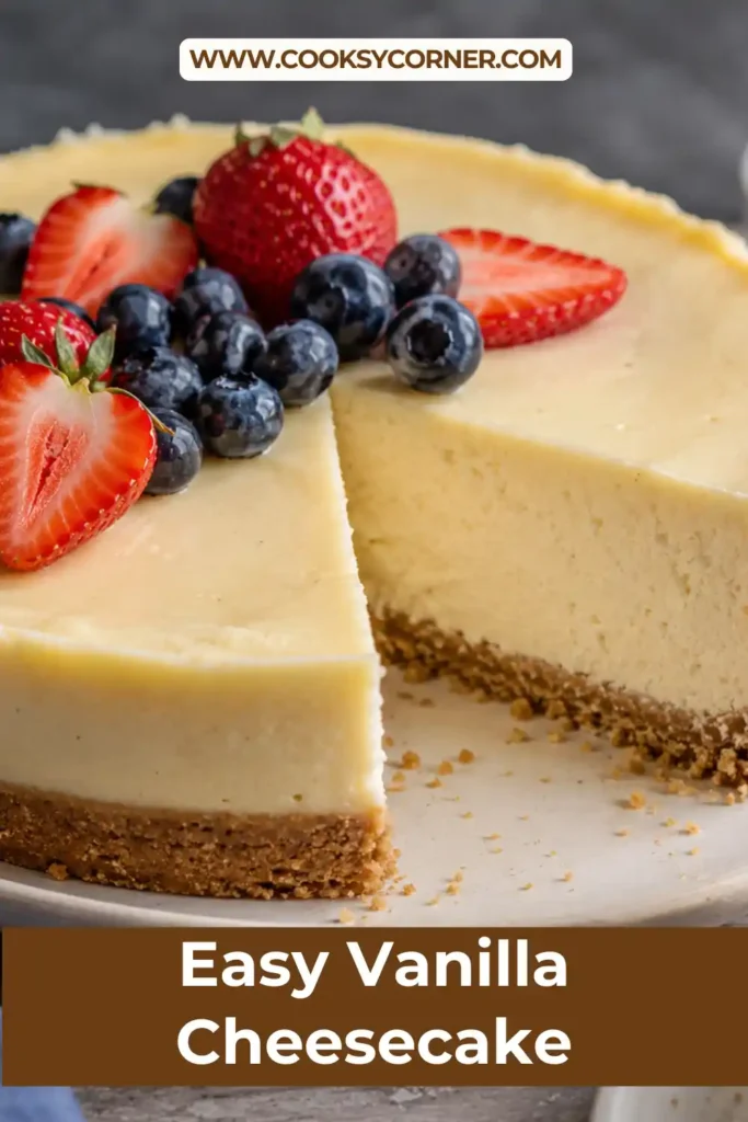 A slice of Vanilla Cheesecake with a buttery biscuit crust and smooth creamy filling served on a white dessert plate. This classic no-bake cheesecake is topped with fresh berries and mint.