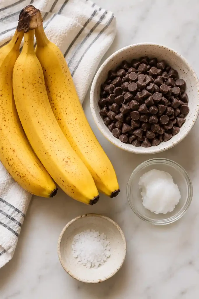 Chocolate-coated banana bites served on a chilled platter with fresh banana slices nearby. These frozen desserts are perfect for summer entertaining and healthy snacks.