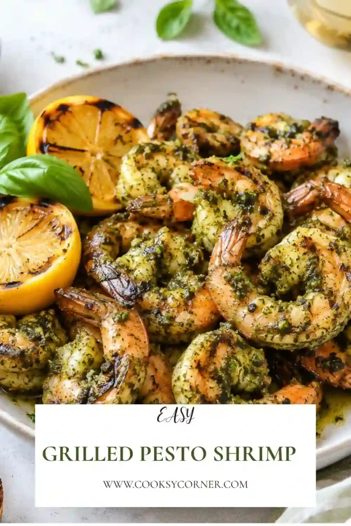 Juicy grilled pesto shrimp served with fresh lemon wedges on a white serving platter. The shrimp are coated in vibrant basil pesto with light char marks from the grill.