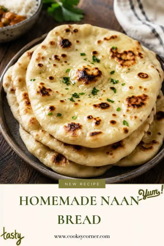 Fresh Homemade Naan Bread stacked on a plate with golden brown bubbles and a soft, fluffy texture. This easy skillet naan is brushed with butter and sprinkled with fresh herbs.