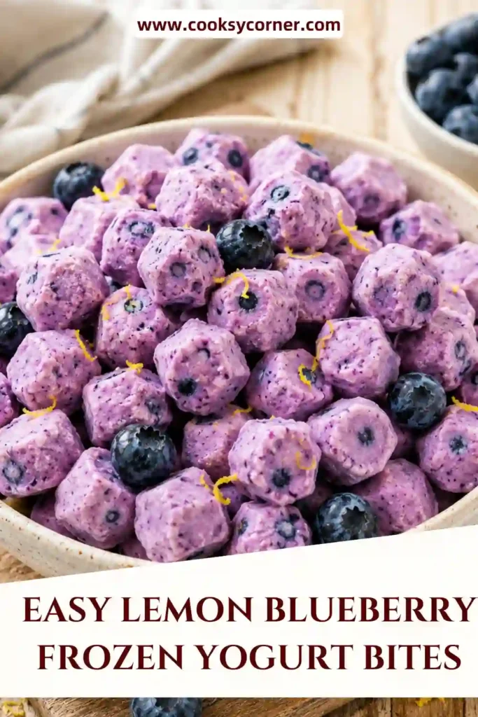 Frozen blueberries coated in creamy lemon Greek yogurt arranged on parchment paper. These Lemon Blueberry Frozen Yogurt Bites are an easy high-protein dessert.
