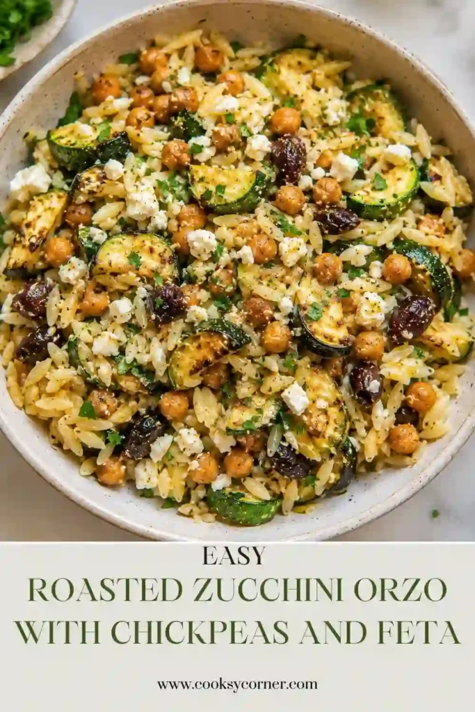 A bowl of Roasted Zucchini Orzo with golden roasted zucchini, crispy chickpeas, creamy feta, olives, and fresh parsley. This colorful Mediterranean vegetarian pasta is finished with a bright lemon dressing.