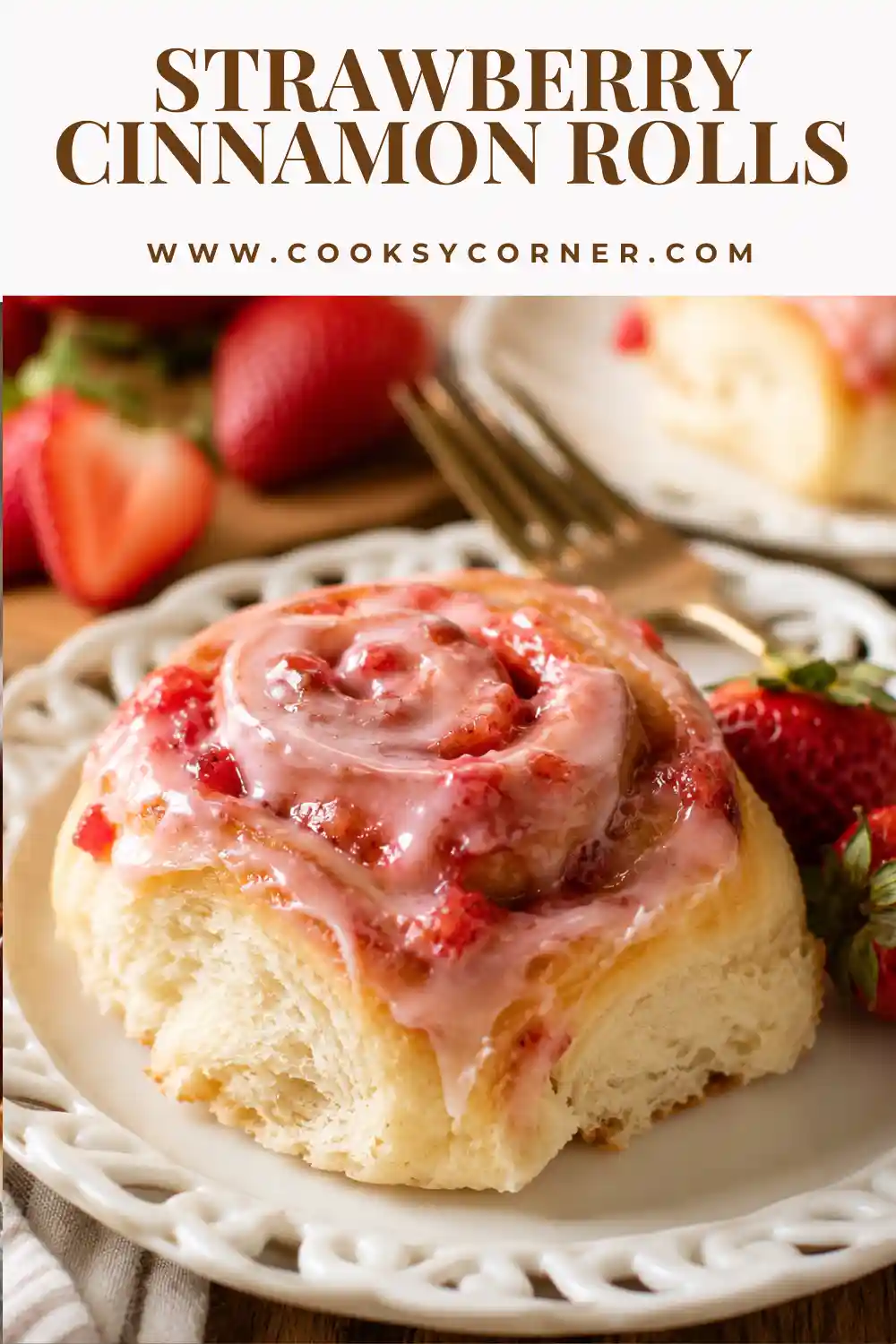 Freshly baked Strawberry Cinnamon Rolls topped with glossy strawberry icing and fresh strawberries in a baking dish.