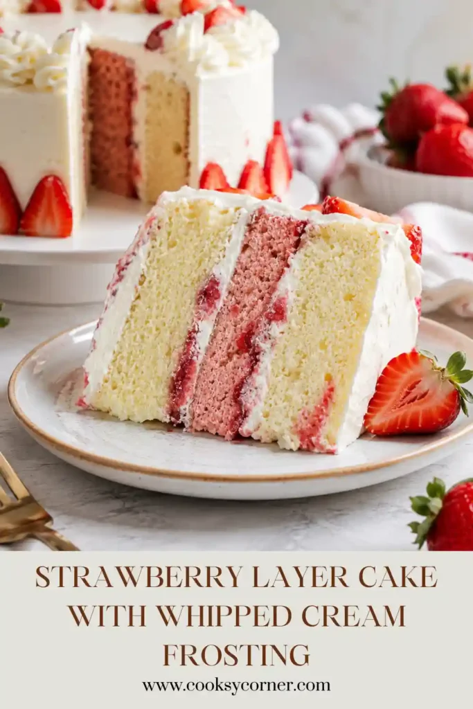 Close-up slice of Strawberry Layer Cake featuring fluffy cake layers, fresh strawberry filling, and creamy whipped frosting garnished with strawberries.