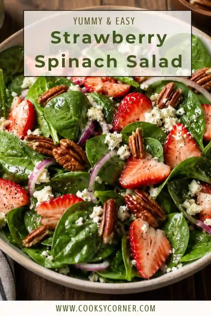 Close-up of a homemade Strawberry Spinach Salad topped with sliced strawberries, feta cheese, toasted pecans, and fresh cracked black pepper.