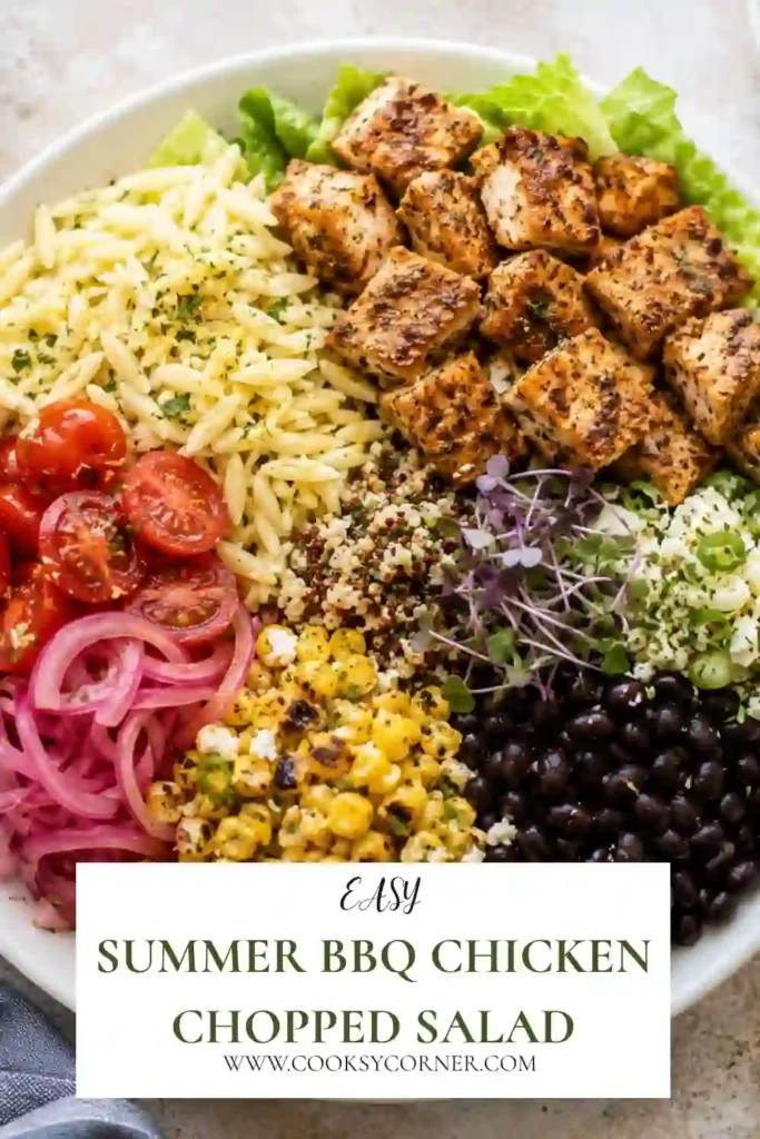 Close-up of Summer BBQ Chicken Chopped Salad featuring caramelized BBQ chicken, grilled corn, black beans, tomatoes, pickled onions, cheddar cheese, and crisp romaine lettuce.