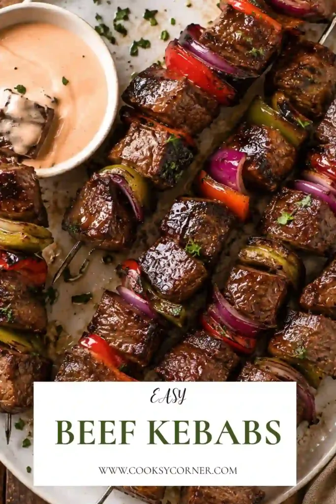 Grilled Beef Kebabs made with juicy steak, bell peppers, onions, and mushrooms on metal skewers. The kebabs are lightly charred and garnished with fresh parsley.