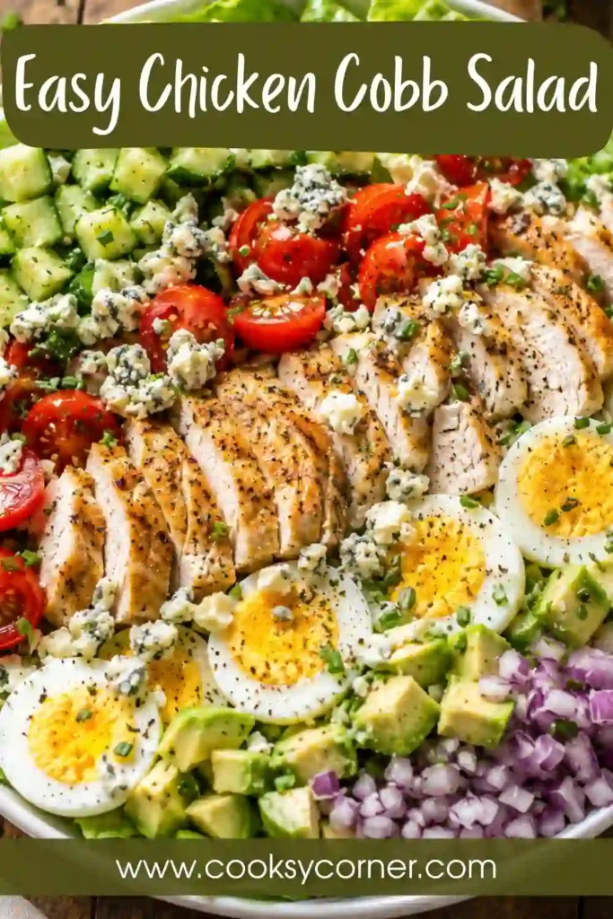 A large serving platter filled with Chicken Cobb Salad featuring grilled chicken, eggs, cucumber, tomatoes, avocado, and blue cheese.