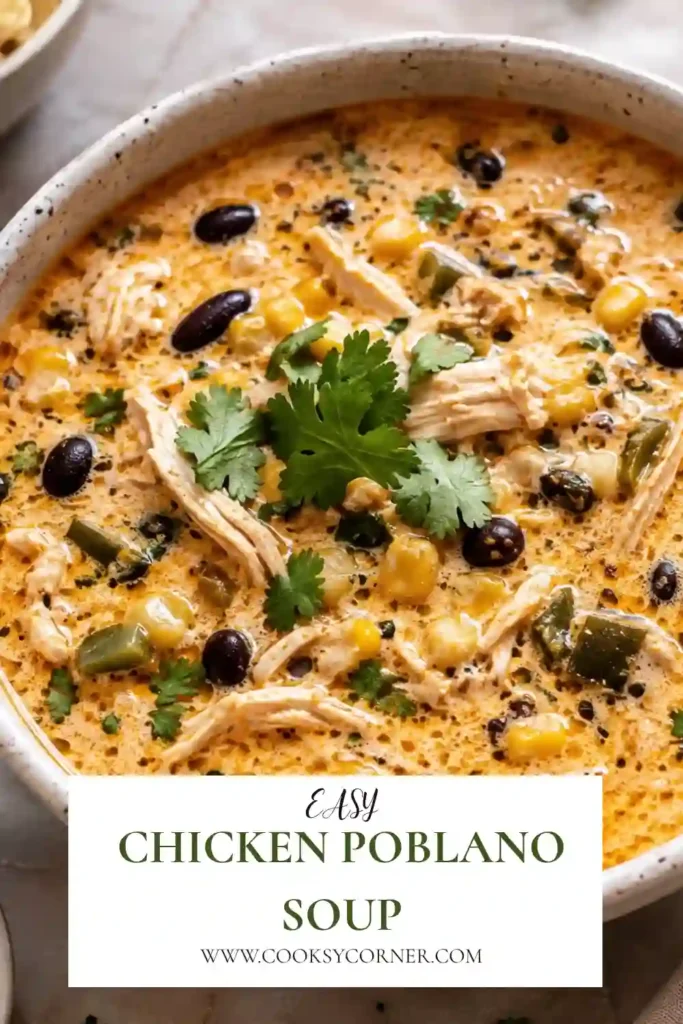 A bowl of creamy Chicken Poblano Soup topped with fresh cilantro and shredded cheddar cheese. The soup is filled with tender shredded chicken, black beans, sweet corn, and smoky poblano peppers in a rich, cheesy broth.