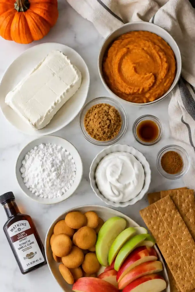 Bowl of no bake pumpkin dip ready for serving with crisp apple slices and graham crackers. This fluffy pumpkin dip is a creamy, warmly spiced autumn dessert.