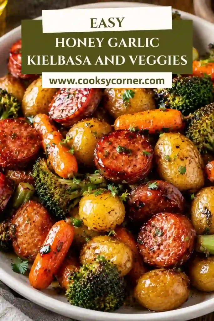 Honey Garlic Kielbasa and Veggies roasted on a sheet pan with baby potatoes, broccoli, red and yellow bell peppers, and carrots. The sausage and vegetables are coated in a glossy honey garlic sauce.