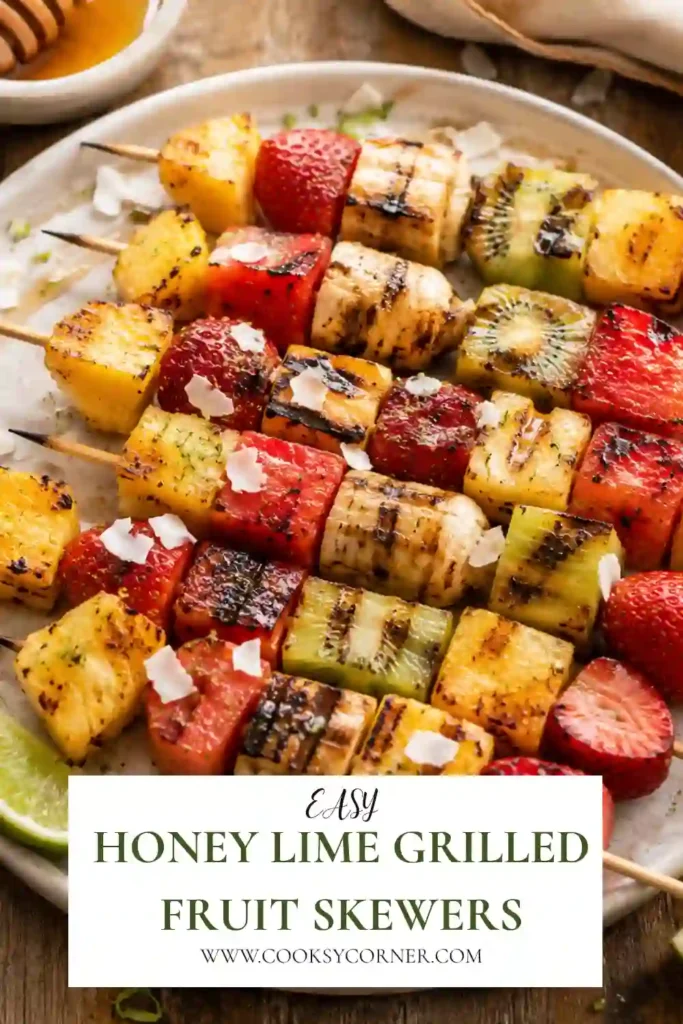 Grilled fruit kabobs featuring strawberries, pineapple, bananas, kiwi, watermelon, and mango with beautiful grill marks and fresh lime wedges.