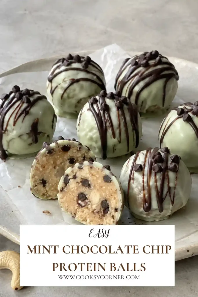 No-bake mint chocolate protein balls arranged on parchment with a smooth chocolate coating and mini chocolate chip topping. The centers are made with cashews, protein powder, honey, coconut oil, and peppermint.