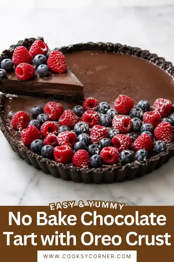 No-Bake Chocolate Tart with a dark Oreo cookie crust and silky chocolate ganache filling. Fresh raspberries, blueberries, and strawberries add a colorful finish with powdered sugar.