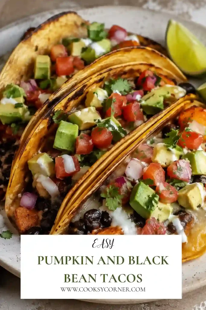 Pumpkin and Black Bean Tacos filled with creamy seasoned pumpkin, refried black beans, and melted cheese inside crispy corn tortillas. The tacos are served warm with fresh avocado and salsa.