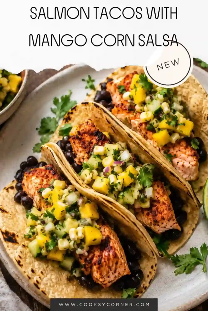 Easy salmon tacos topped with fresh mango corn salsa on a rustic serving platter. Lime wedges and cilantro complete this colorful seafood taco recipe.