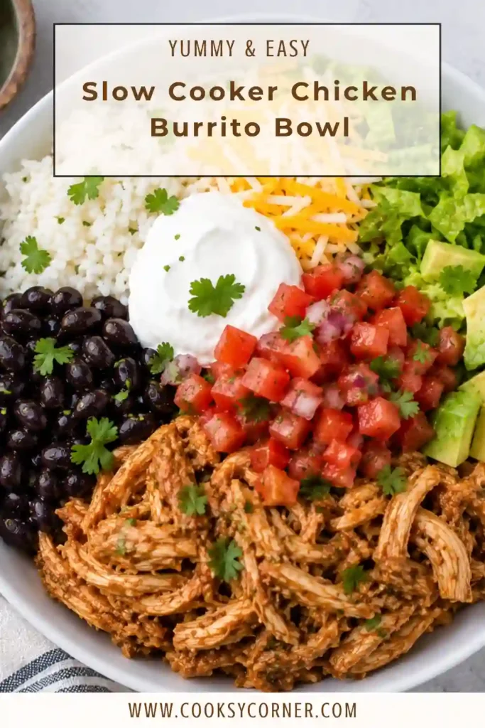 Healthy chicken burrito bowl topped with slow cooker Mexican chicken, black beans, golden corn, creamy avocado, and fresh cilantro. Lime wedges add a bright citrus finish.