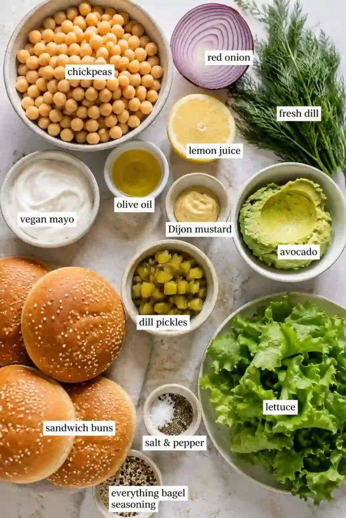 4. Smashed Chickpea Avocado Sandwich featuring a chunky avocado chickpea salad with dill pickles and fresh herbs. The sandwich is layered with crisp greens for a fresh plant-based lunch.