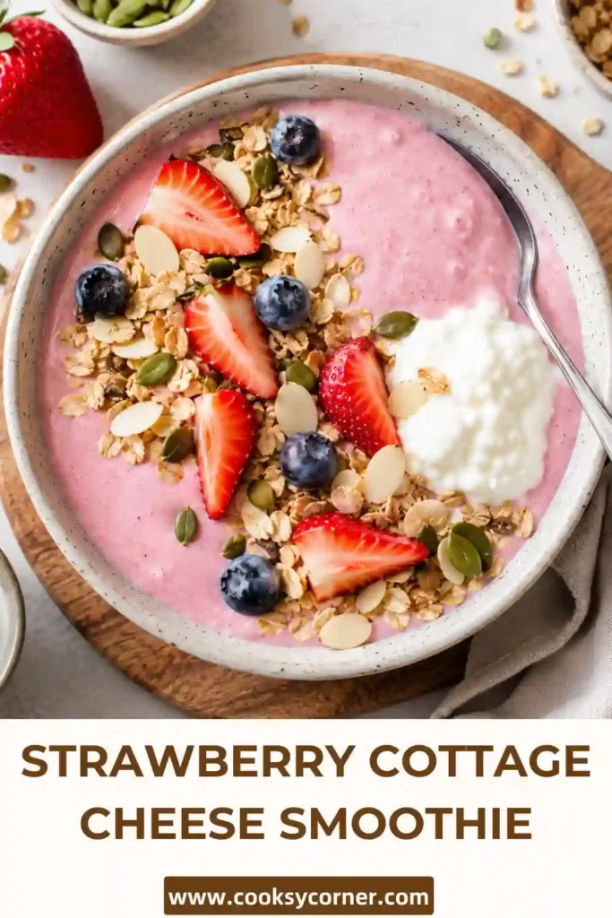 A creamy Strawberry Cottage Cheese Smoothie Bowl topped with fresh strawberries, granola, blueberries, almonds, and chia seeds in a ceramic bowl. This high-protein breakfast is colorful, refreshing, and nutritious.