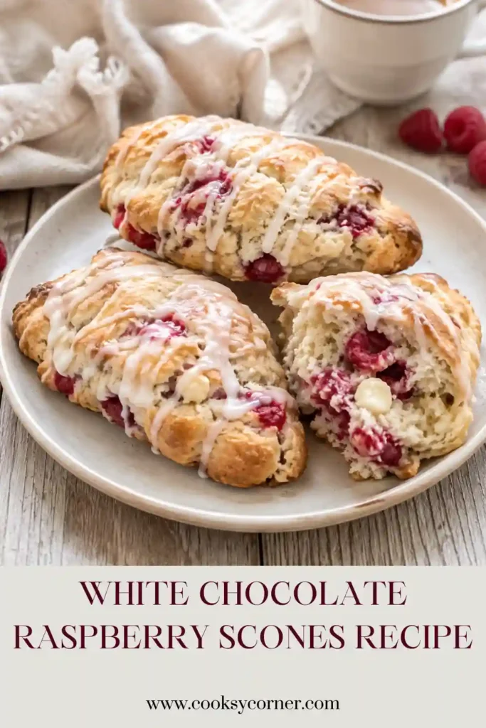 Freshly baked White Chocolate Raspberry Scones arranged on a serving plate with raspberries and white chocolate pieces. The tender scones are finished with a delicate sweet glaze.