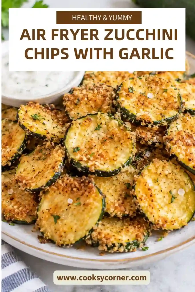 Air fryer zucchini chips served in a small bowl with golden edges and visible garlic seasoning. The thin zucchini rounds have lightly browned surfaces and delicate crisp edges