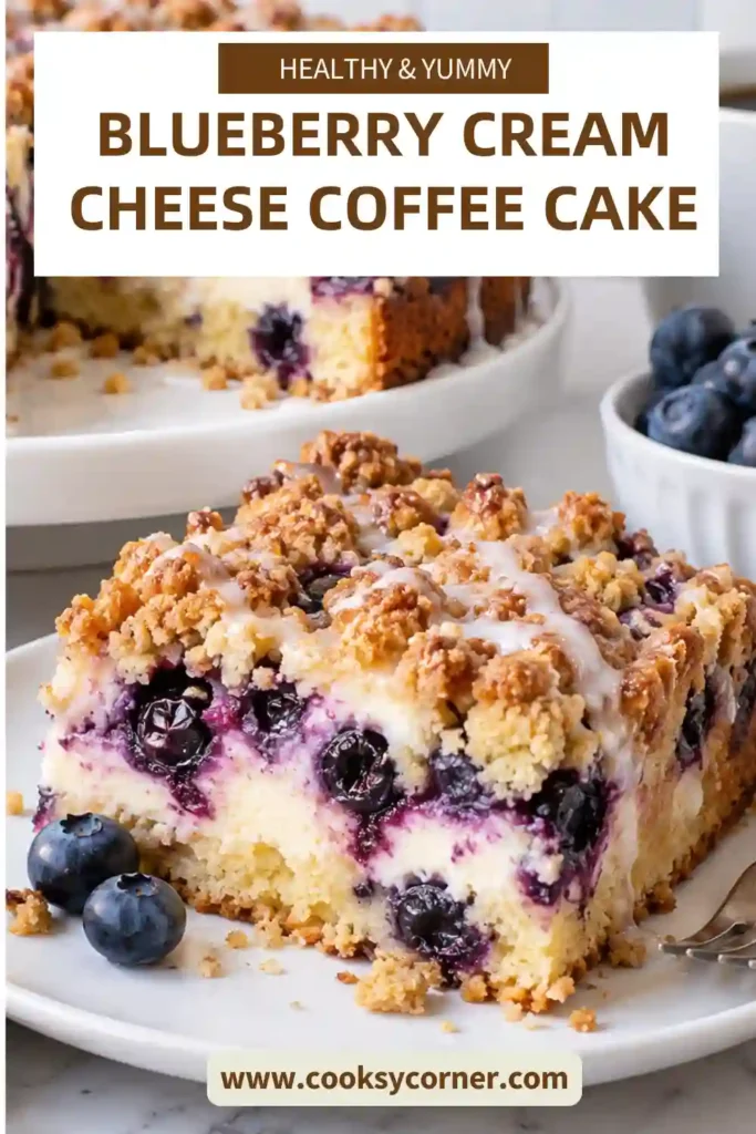 Blueberry Cream Cheese Coffee Cake topped with golden brown sugar crumble and a light dusting of confectioners' sugar. Juicy blueberries and creamy filling are visible throughout each thick slice.