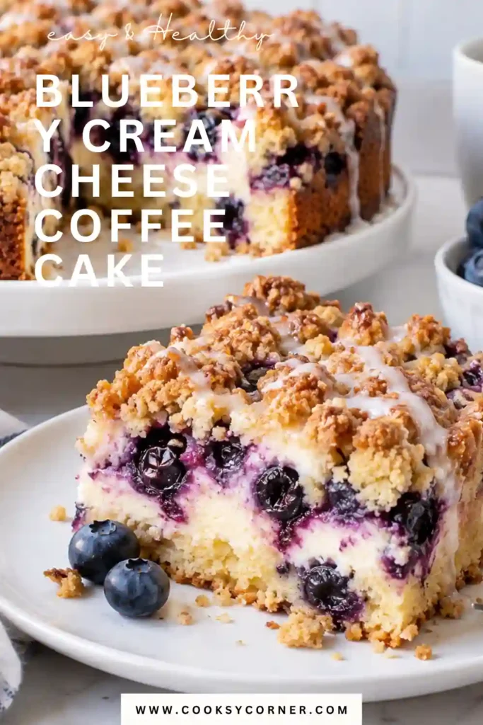 Blueberry Cream Cheese Coffee Cake sliced to reveal a creamy cheesecake-style center surrounded by tender cake packed with fresh blueberries. A golden cinnamon crumble and confectioners' sugar cover the top.