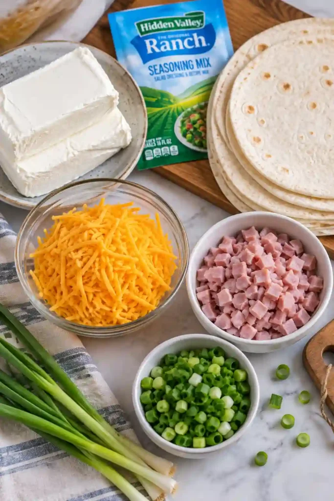 Turkey ham roll ups with creamy cheese, ranch seasoning, cheddar, and fresh green onions wrapped in soft flour tortillas. The chilled pinwheels are arranged as an easy party appetizer.